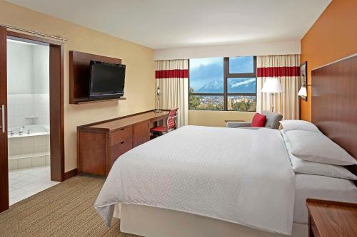 Cette chambre comprend un grand lit et une télévision. dans l'établissement Grand Park Hotel Vancouver Airport, Ascend Hotel Collection, à Richmond