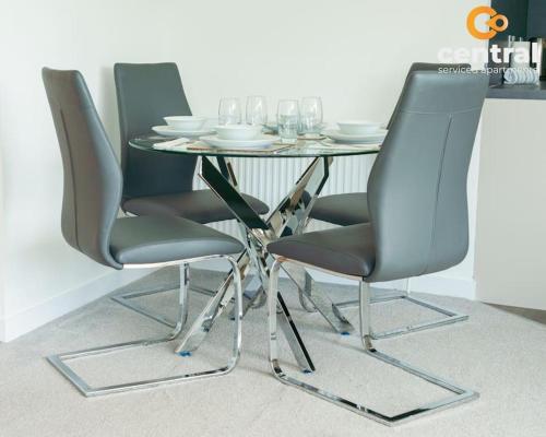 a dining room table with two chairs and a table with wine glasses at City Quay by CENTRAL SERVICED APARTMENTS - 2 Bedrooms - City Quay Views - Walk Into Dundee City Centre - Walk Away From Bus & Train Station - Lift Access in Dundee