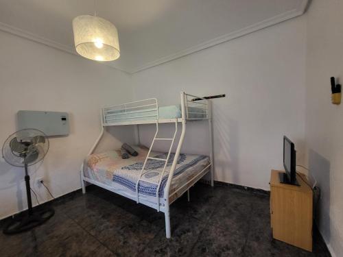 a bedroom with a bunk bed with a lamp and a television at Casa Oasis Puertollano, una casa rural en Puertollano, agradable, con Piscina en zona tranquila in Puertollano