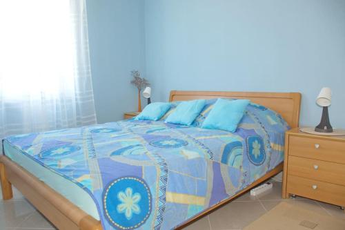 a bedroom with a bed with a blue comforter at Beachside Babe in Novalja
