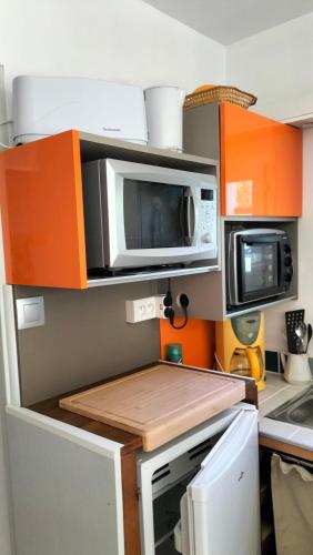 - une cuisine avec des armoires orange et un four micro-ondes dans l'établissement Fenouillet, à Hyères