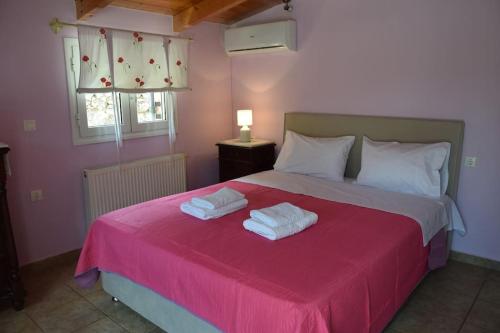a bedroom with a pink bed with two towels on it at Mountain Breeze Cottage in Makriótika