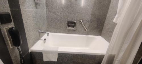 a white bath tub in a bathroom with a phone at Hotel Marine Plaza in Mumbai