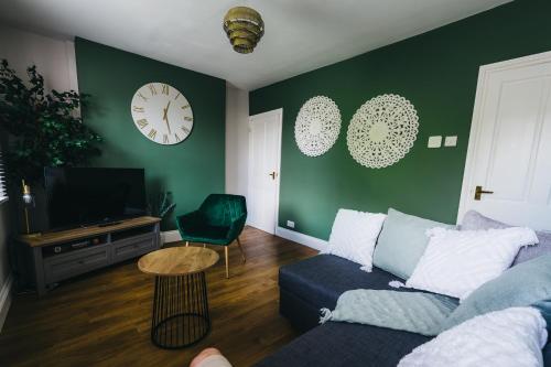 a living room with a couch and a clock on the wall at Leam Terrace Escape in Leamington Spa