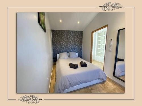 a bedroom with a white bed with two black shoes on it at Charmant duplex avec tropézienne in Vidauban