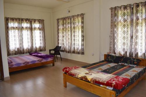a bedroom with two beds and a chair in it at Riwar Homestay in Mawlynnong