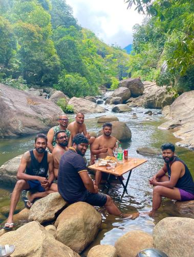 a group of men sitting around a table in a river at Citrine Belihuloya in Belihul Oya