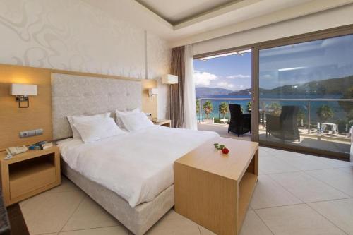 a bedroom with a large bed and a large window at Ionian Emerald Resort in Karavomylos