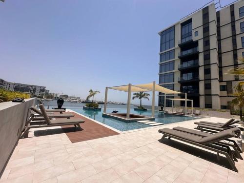a swimming pool with lounge chairs and a building at Luxury hotel flat in Ḩayl Āl ‘Umayr