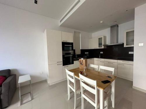 a kitchen with a wooden table and white cabinets at Luxury hotel flat in Ḩayl Āl ‘Umayr