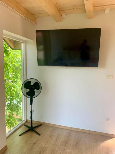 a television on the wall of a room with a fan at Mazurski dom Brejdyny Sauna i Bania in Mrągowo