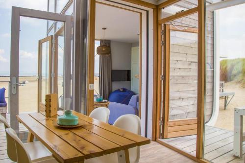 a dining room with a table and a view of the beach at Strandhuis, Beachhouse - Slapen op het strand, Sleep at the beach in Nieuwvliet