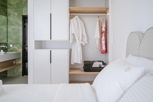 a bedroom with a white bed and a closet at Sardines Luxury Suites in Hersonissos