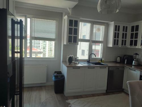a kitchen with white cabinets and a sink and windows at Zumra's White Houses in Trabzon