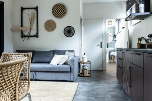 a living room with a blue couch and a kitchen at Appartement Beau Séjour - Accès Piscine in Criel-sur-Mer