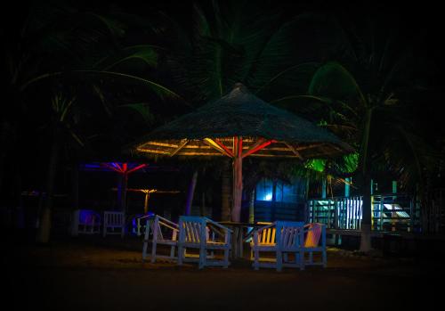 a group of chairs and an umbrella on the beach at night at Atlantic Bay Resort, Prampram in Prampram