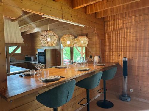 une cuisine avec un grand bar en bois et des chaises dans l'établissement Chalet dans un écrin de verdure avec SPA privatif, à Jeanménil