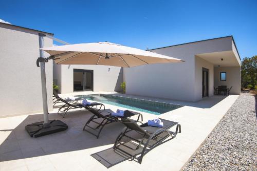 un patio avec des chaises et un parasol ainsi qu'une piscine dans l'établissement Villa Nauta - beautiful ground floor villa for 4 people with playground & sauna Pula, à Vintijan