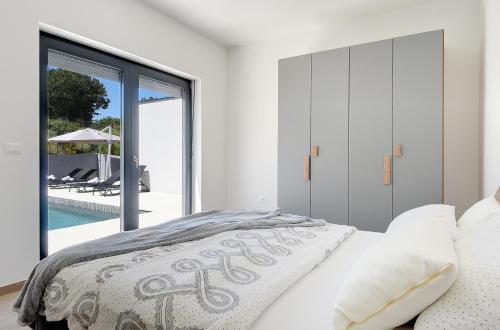 une chambre avec un lit et une vue sur une piscine dans l'établissement Villa Nauta - beautiful ground floor villa for 4 people with playground & sauna Pula, à Vintijan