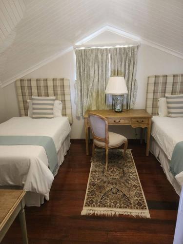 a bedroom with two beds and a desk and a chair at Stone Town Guesthouse in Gaborone