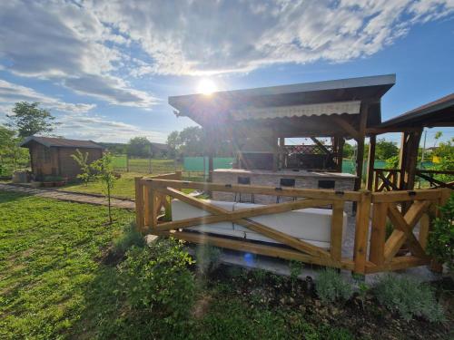 a picnic shelter in a field with the sun shining at DRiM Wood House - no party house in Lasinja