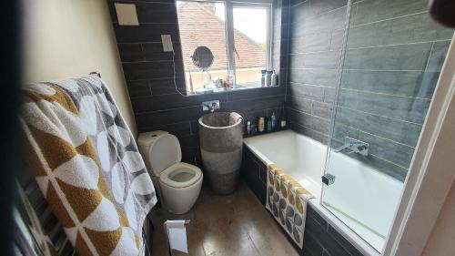 a bathroom with a tub and a toilet and a window at The Homestay in High Wycombe