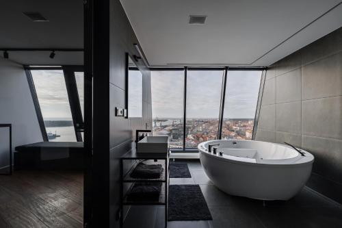 a bathroom with a large tub in front of a window at Sky Garden Penthouse in Klaipėda