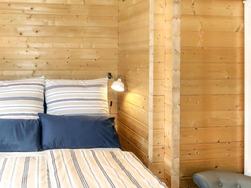 a bedroom with wooden walls and a bed with blue pillows at Holiday Home Ferienhaus Barbara by Interhome in Enspel