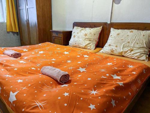 an orange comforter with white stars on a bed at Holiday Home Kern by Interhome in Kvasiny