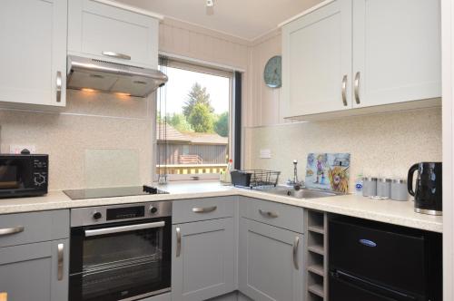 a kitchen with white cabinets and a sink and a window at Blairlagan Lodge in Hunters Quay