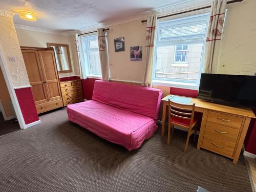 a pink couch in a room with a desk at Lindisfarne Holiday Apartments - Families & Couples Only in Blackpool