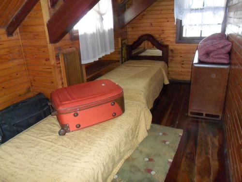 a room with two beds with a red suitcase on it at Suite No Centro De Gramado in Gramado