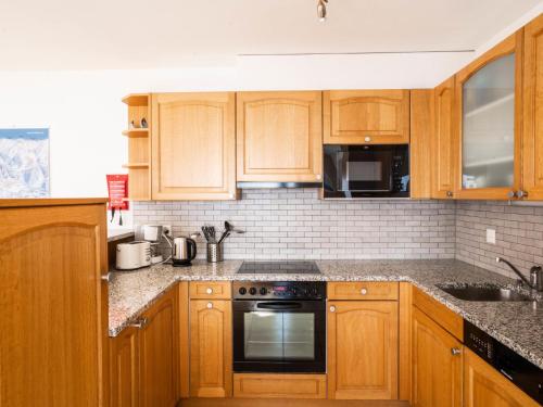 a kitchen with wooden cabinets and a stove top oven at Apartment Les Cîmes 4 by Interhome in Les Collons