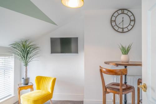 a room with a table and chairs and a clock at Gorgeous New 1 Bedroom Penthouse Flat in Morecambe