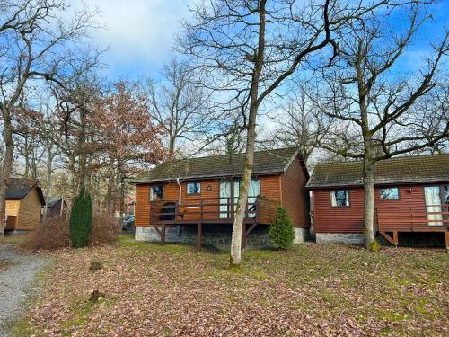 Una gran casa de madera con árboles delante de ella. en Le Bochetay 13, en Somme-Leuze
