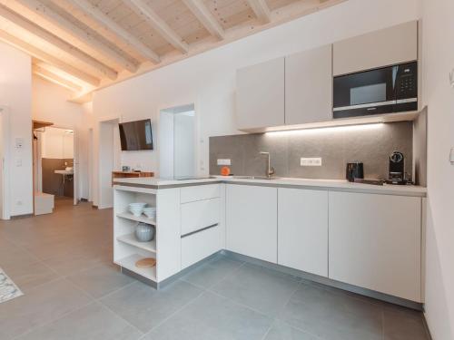 a kitchen with white cabinets and a microwave at Apartment Das Georgen- Großglockner-Kitzsteinhorn by Interhome in Fürstau