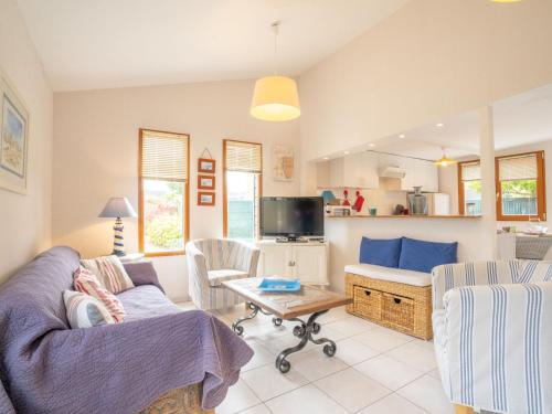 Una sala de estar con un sofá y sillas y un televisor. en Chalet Les Hortensias by Interhome, en Trébeurden