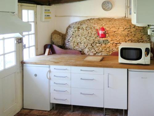 - une cuisine avec un comptoir, un four micro-ondes et un mur en pierre dans l'établissement Holiday Home Marquefabe by Interhome, à Puymiclan