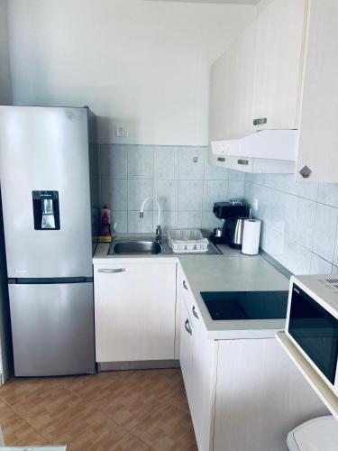 a white kitchen with a refrigerator and a sink at Apartments Juraković in Živogošće