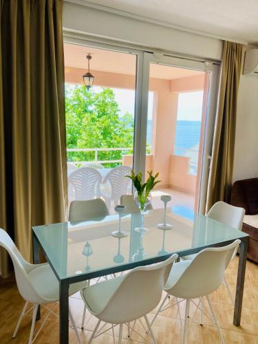 a dining room with a glass table and white chairs at Apartments Juraković in Živogošće