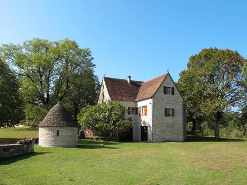 une ancienne maison en pierre avec un moulin à vent dans un champ dans l'établissement Holiday Home La Bergerie de Durand by Interhome, à Saint-Chamarand