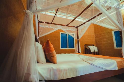 a bedroom with a canopy bed with white sheets and pillows at Yakaduru - Yala in Yala