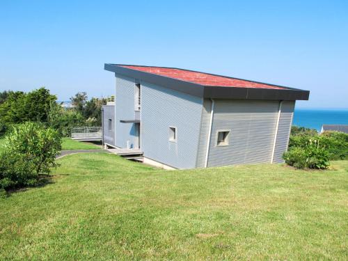 un petit bâtiment avec un toit rouge sur une pelouse dans l'établissement Holiday Home Gwel Ar Mor by Interhome, à Plonevez-Porzay