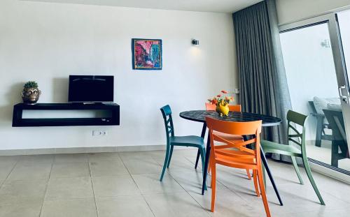 Un comedor con mesa y sillas y un televisor. en # Blue Bay Beach - Ocean View Apartments - FULLY AIR CONDITIONED #, en Blue Bay
