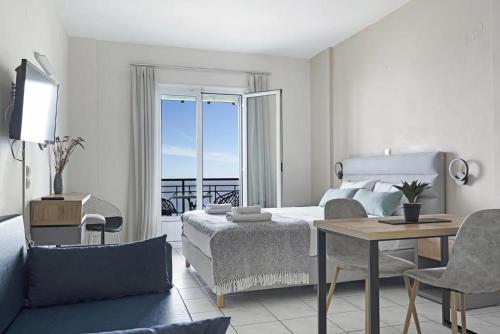 a bedroom with a bed and a table and a room with a balcony at Sunset Premium Studio 6 in Agios Nikitas