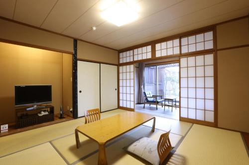 a living room with a table and a tv at Miyahama Grand Hotel in Hatsukaichi