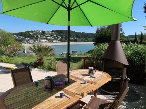 - une table en bois avec un parasol vert sur la terrasse dans l'établissement Holiday Home Meeresblick by Interhome, à Kerouguel