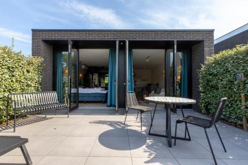 a patio with a table and chairs and a building at Welcome in - Luxe vakantiewoningen nabij strand ZEEBRIES - Dishoek in Koudekerke