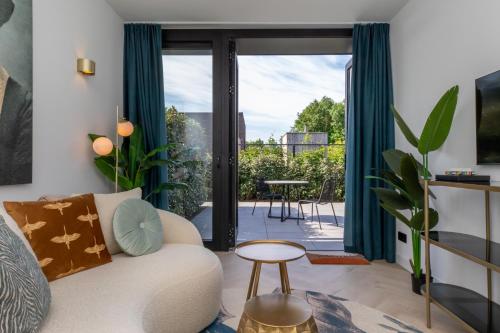 a living room with a couch and a sliding glass door at Welcome in - Luxe vakantiewoningen nabij strand ZEEBRIES - Dishoek in Koudekerke