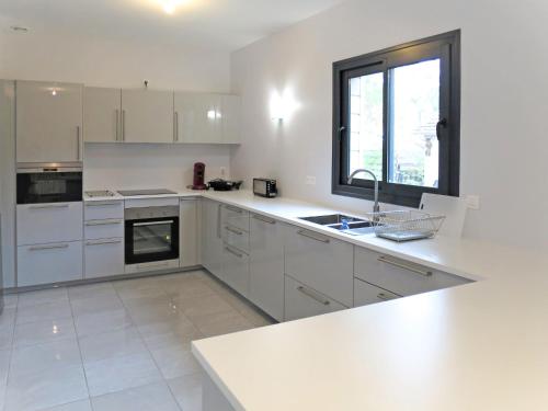 une cuisine avec des armoires blanches, un évier et une fenêtre dans l'établissement Holiday Home Yara by Interhome, à Lacanau